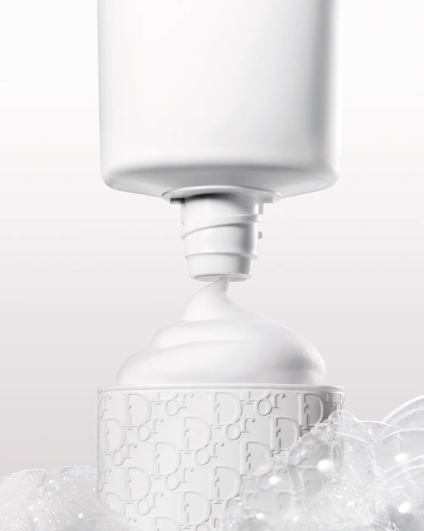 white product dispenser pouring cream into a textured container surrounded by bubbles